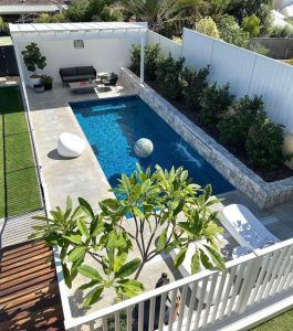 Luxury home with large rectangular dark blue water outdoor pool and shaded sofa area.