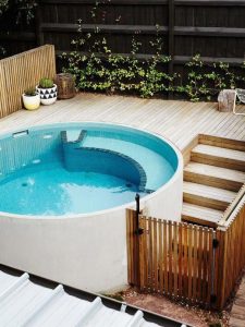 Round above-ground spa pool with stairs access and side fence for safety.