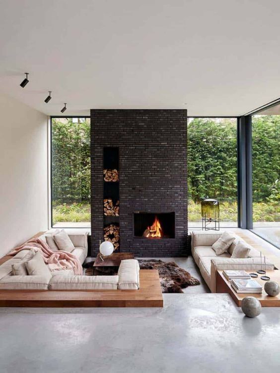 Living room with indoor fireplace, beige sofas, open windows, and cosy home interior design.