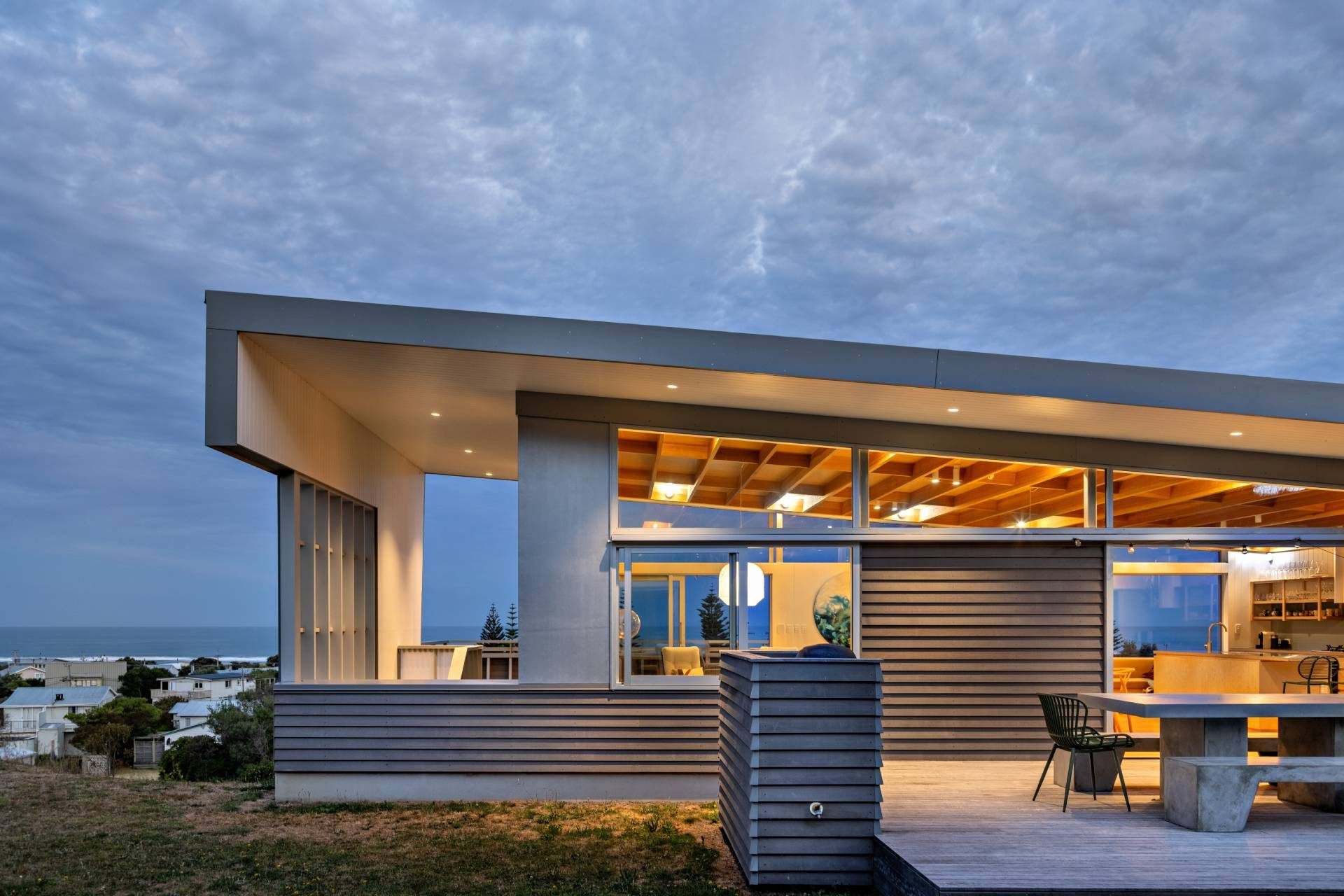 modern coastal home with warm interior lighting and ocean view