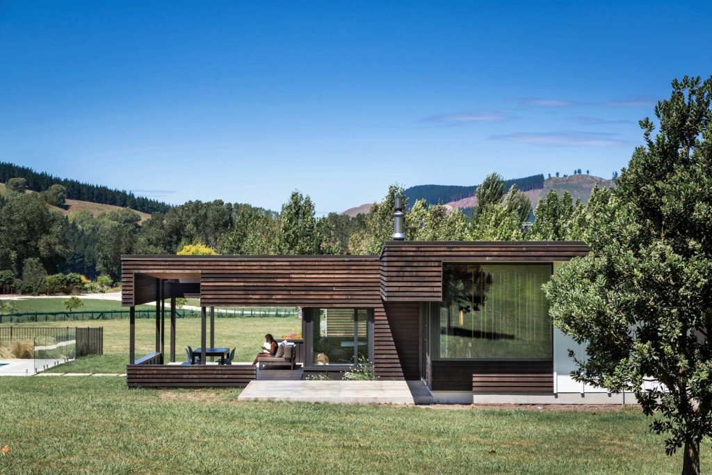 modern wooden home with mountains and trees in the background